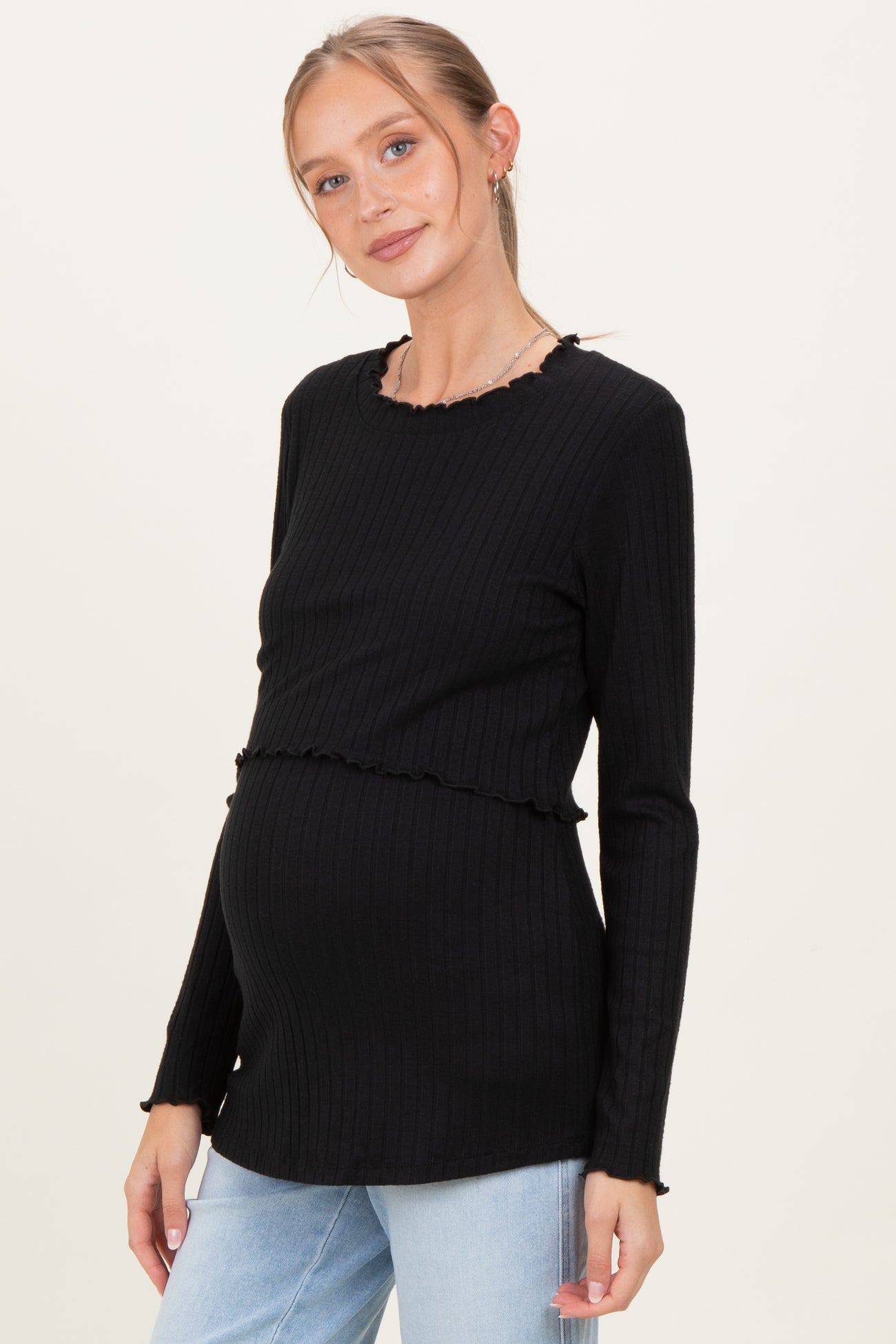 woman wearing a black ribbed maternity top with ruffled hem and a visible baby bump