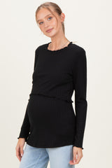 woman wearing a black ribbed maternity top with ruffled hem and a visible baby bump