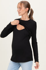 woman wearing a black long sleeve maternity top with a scoop neckline and ruffled detail, showcasing her baby bump