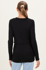 woman wearing a black long sleeve maternity top with ribbed texture and frill details, showing her back