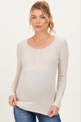woman wearing a beige long sleeve maternity top with button details and a visible baby bump