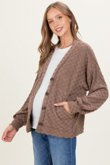 woman wearing a brown waffle knit maternity cardigan over a light gray top and showing her baby bump
