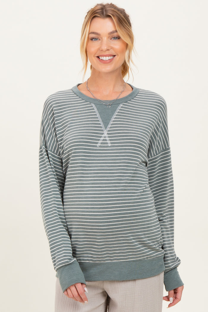 woman wearing a green striped maternity sweatshirt with long sleeves and a relaxed fit, showing her baby bump