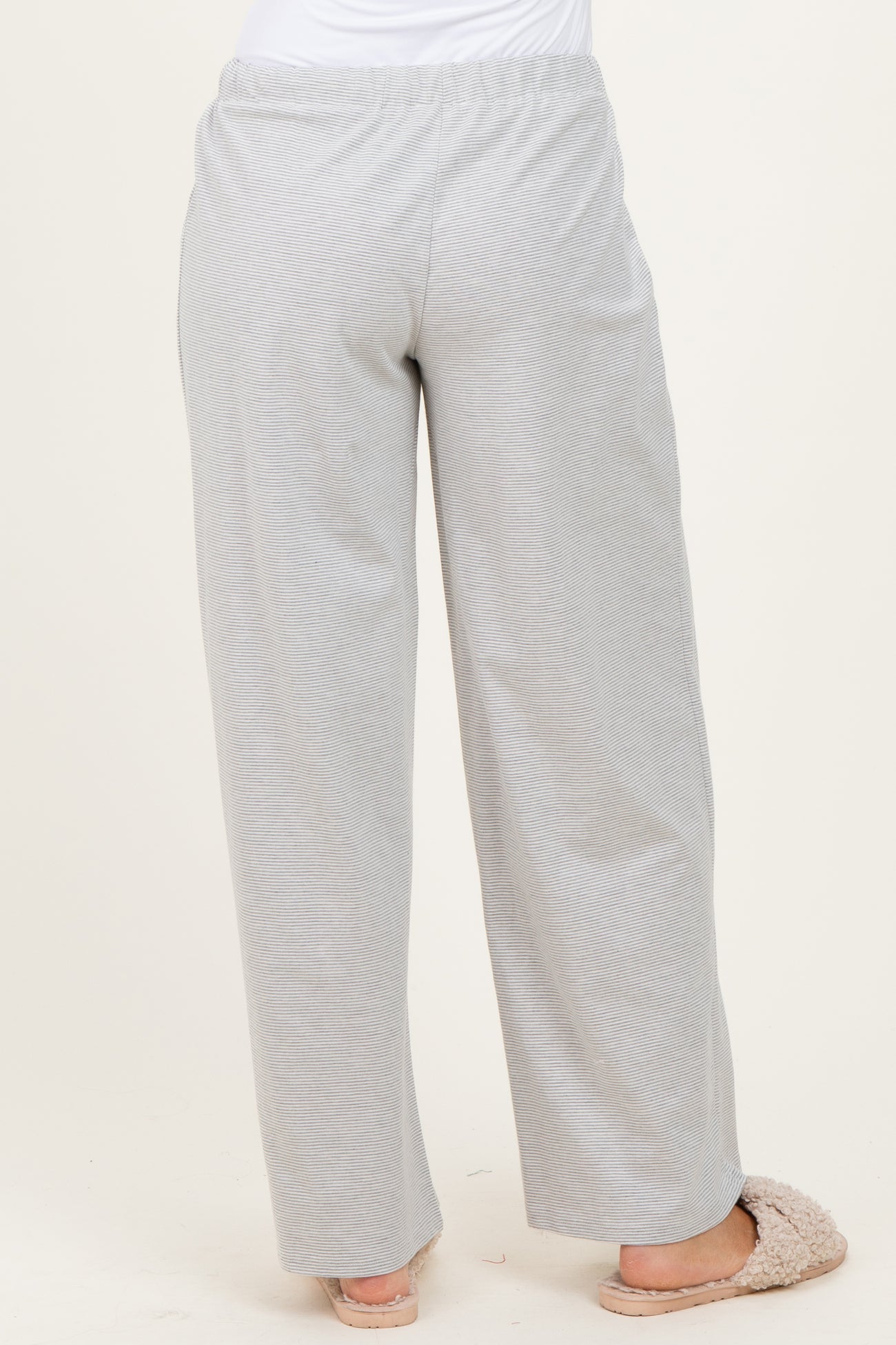 woman wearing light gray wide-leg lounge pants, view from the back, paired with cozy slippers