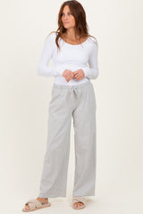 woman wearing a white long sleeve fitted top and light gray drawstring wide-leg pants, with cozy slippers