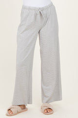 woman wearing light gray wide-leg lounge pants with an elastic waistband and drawstring detail, paired with fluffy slippers