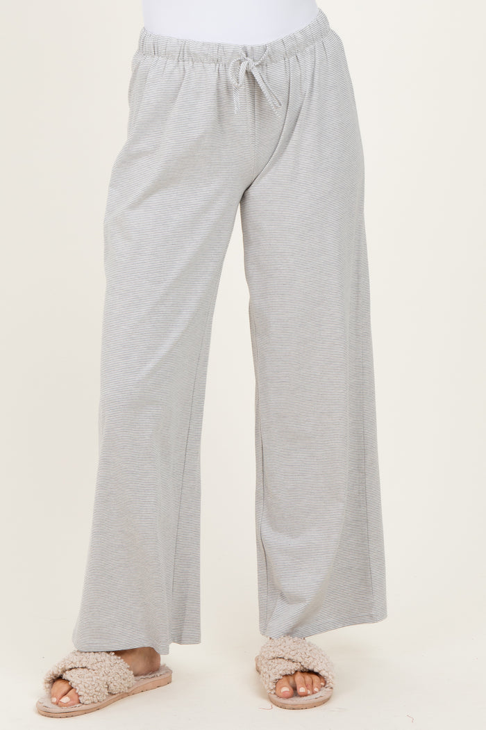 woman wearing light gray wide-leg lounge pants with an elastic waistband and drawstring detail, paired with fluffy slippers