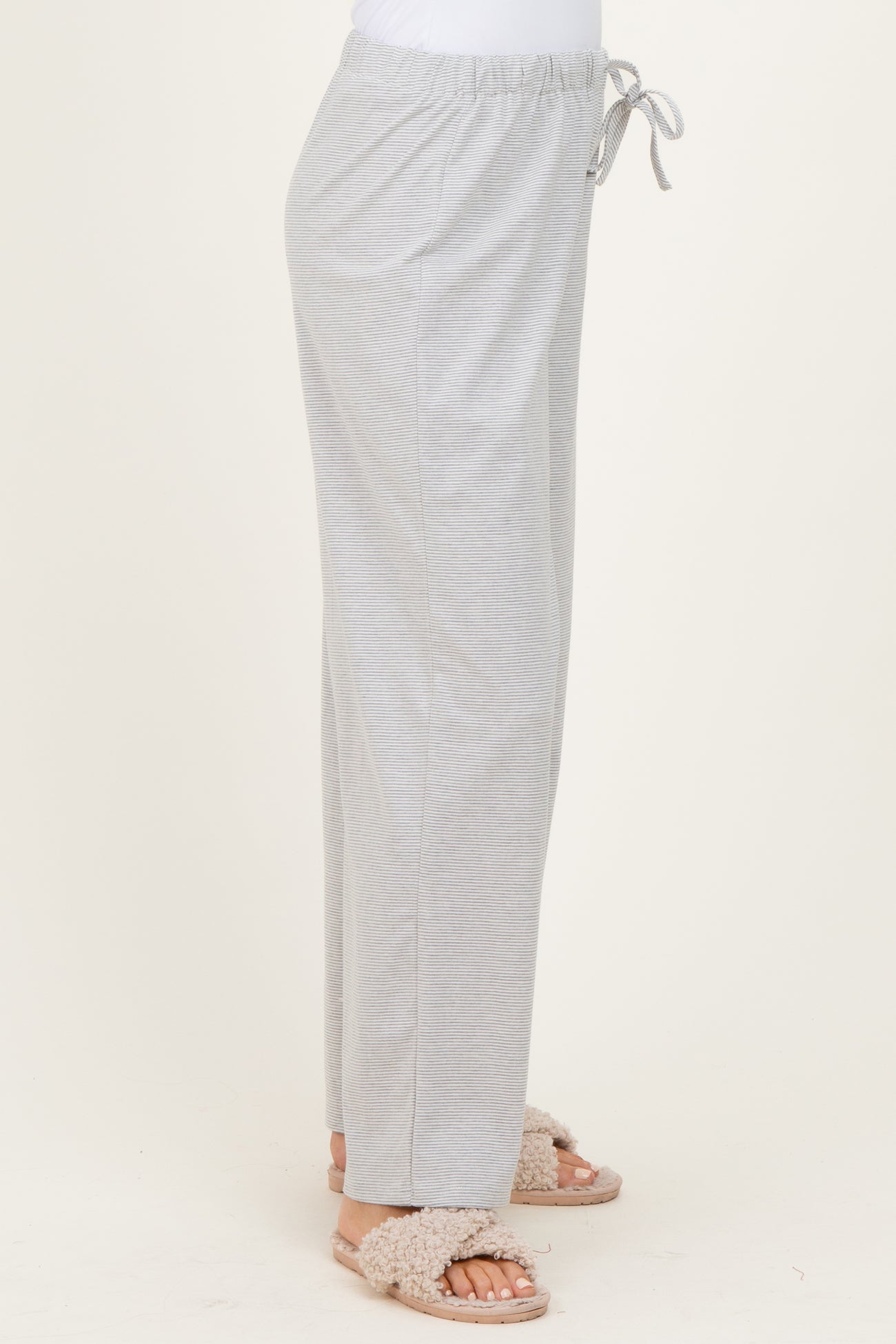woman wearing light gray drawstring lounge pants with side pockets and fluffy sandals