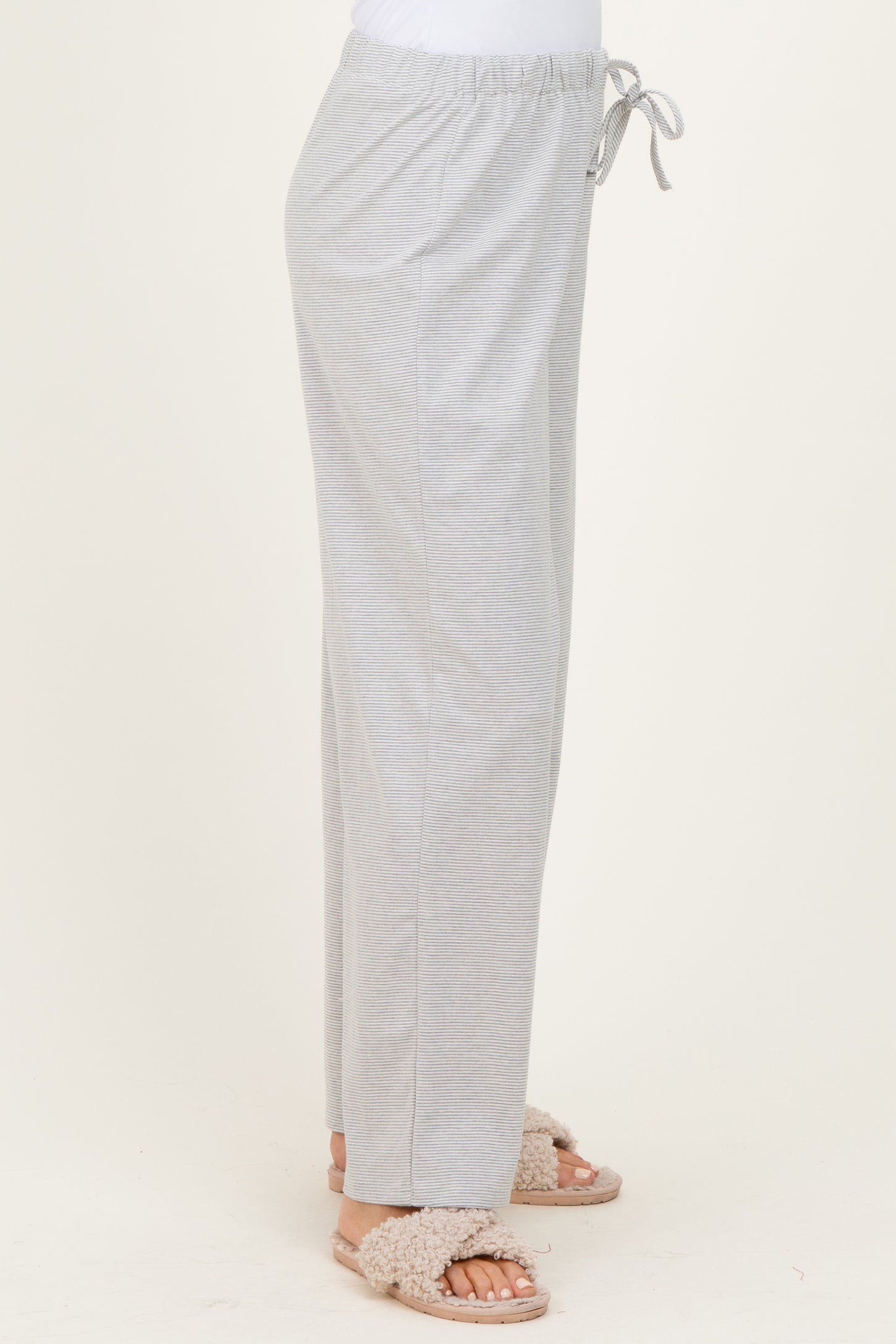 woman wearing light gray drawstring lounge pants with side pockets and fluffy sandals
