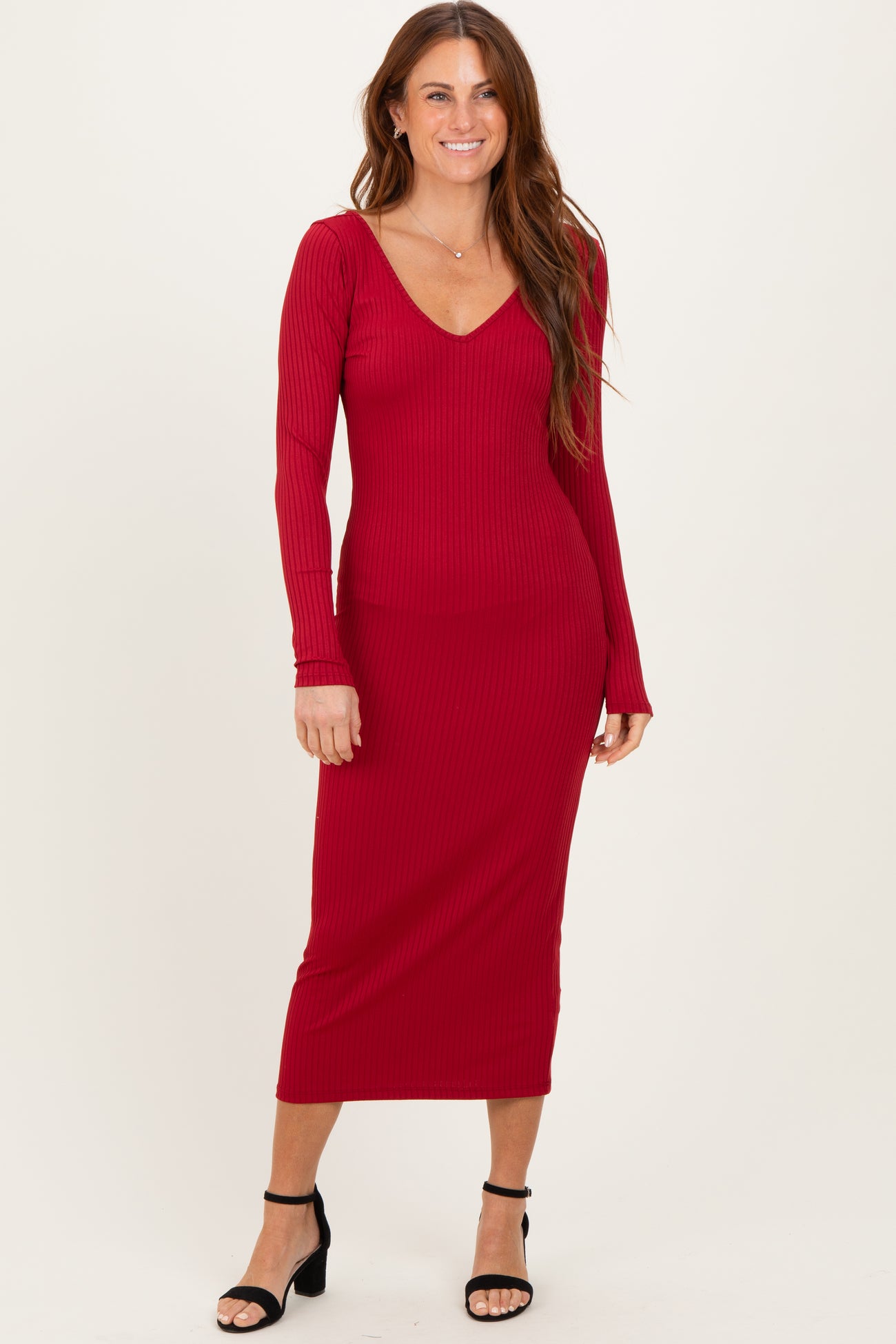 woman wearing a red ribbed long sleeve midi dress with a v-neckline and fitted silhouette