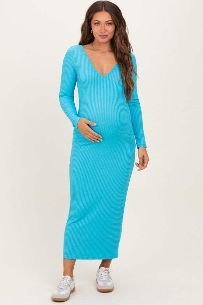 woman wearing a turquoise long sleeve ribbed maternity dress and holding her baby bump