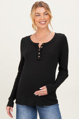 woman wearing a black long sleeve maternity top with buttons and holding her baby bump