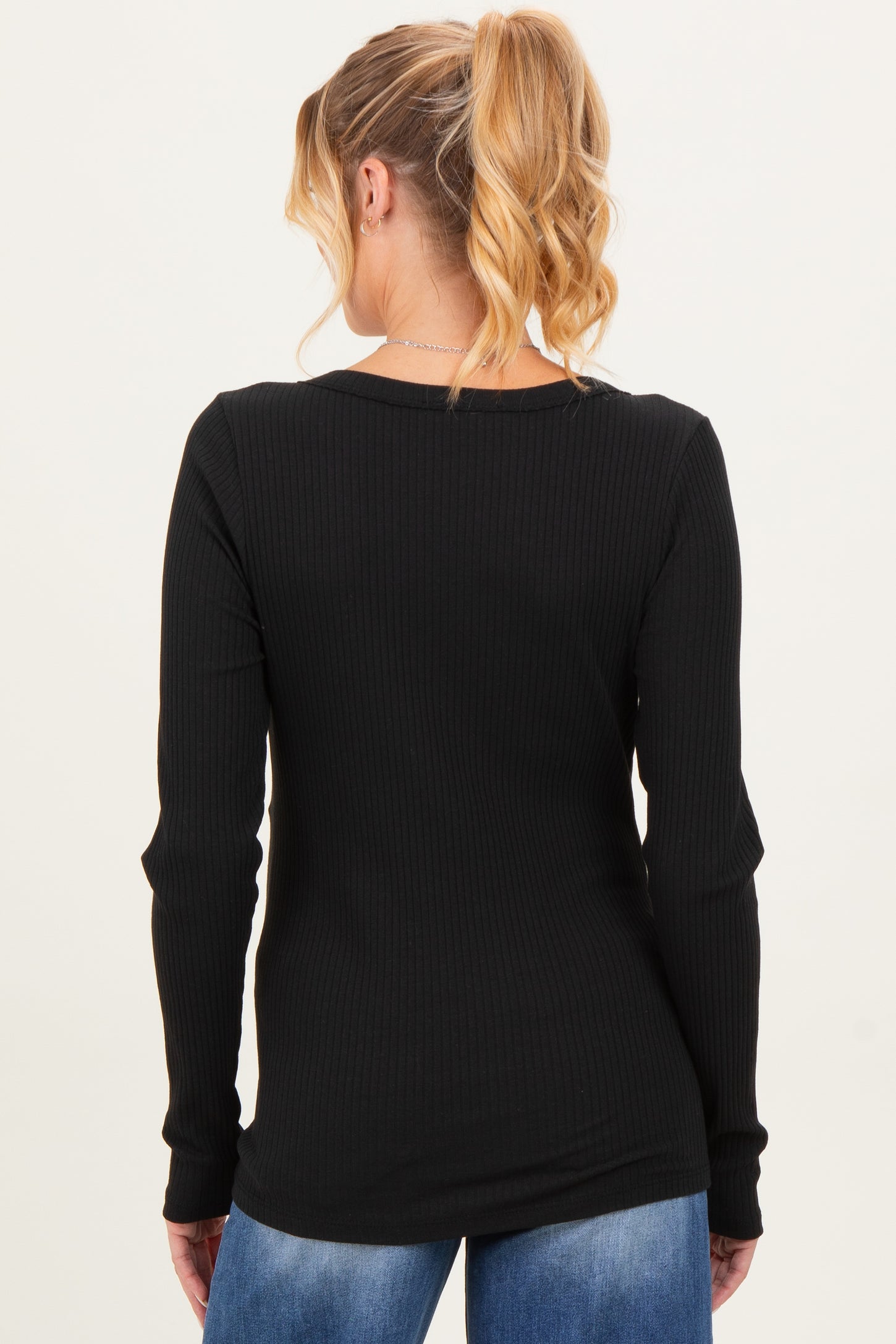 woman wearing a black long sleeve maternity top, viewed from the back with a ribbed texture