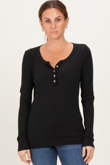 woman wearing a black ribbed long sleeve henley top with button details and paired with blue jeans