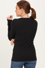 woman wearing a black ribbed long sleeve top, viewed from the back, with a casual ponytail hairstyle