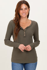 woman wearing an olive green ribbed long sleeve henley top with buttons, smiling and posing with hands on her hips
