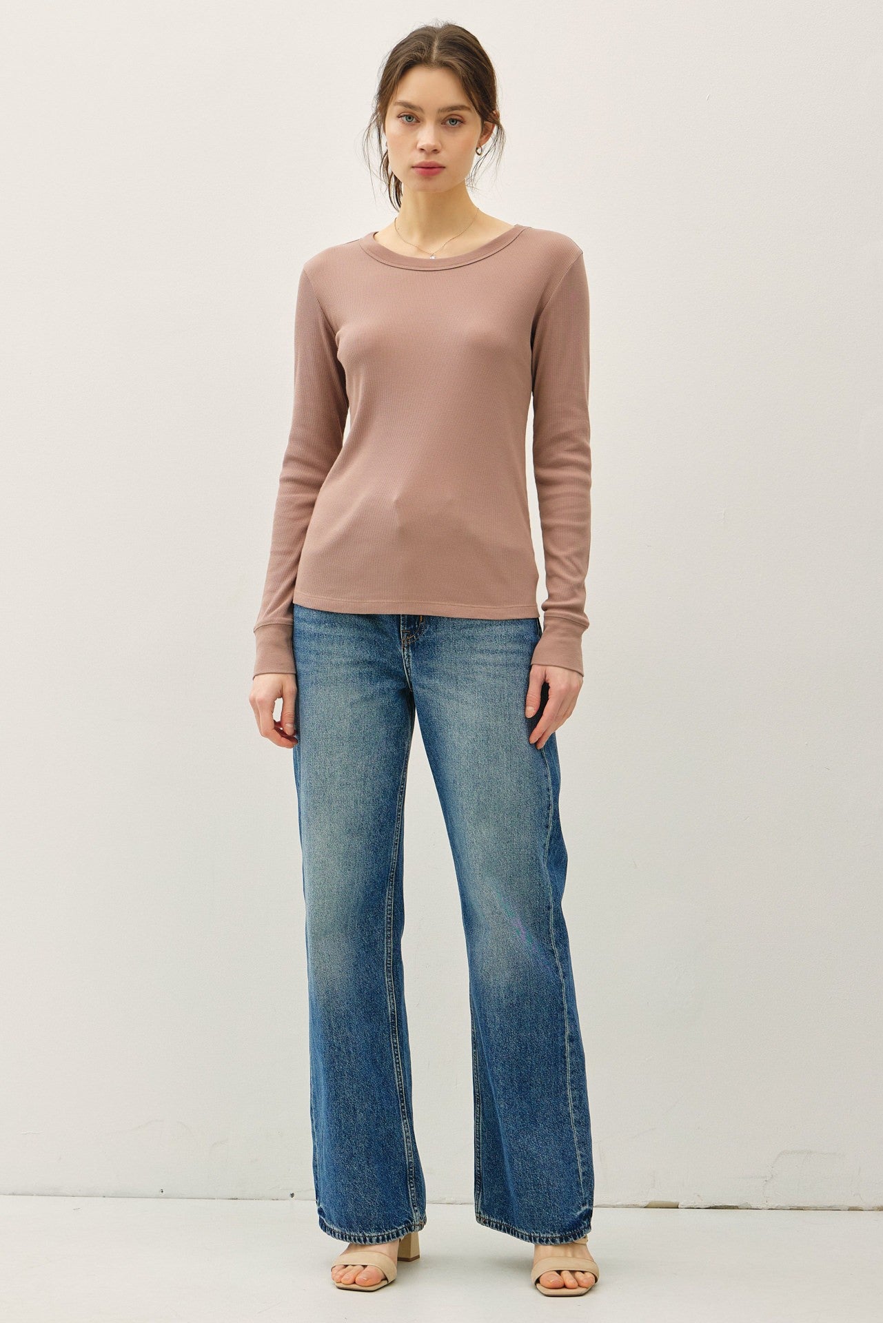 woman wearing a light pink long sleeve top paired with wide leg blue jeans