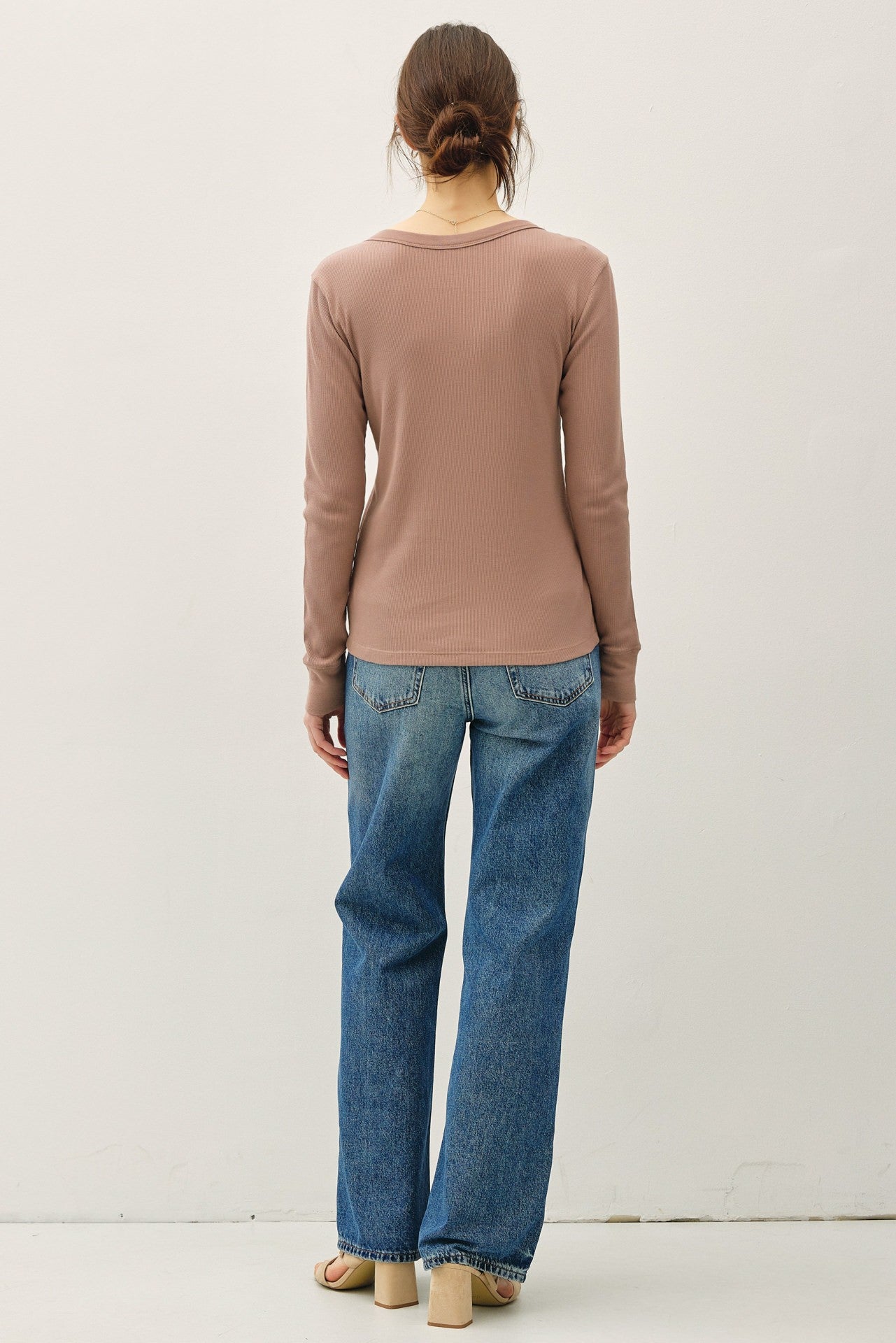 woman wearing a brown long sleeve top with a scoop neckline and relaxed fit paired with light blue wide-leg jeans