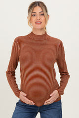 woman wearing a rust striped maternity top and holding her baby bump