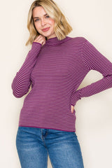 woman wearing a purple and white striped long sleeve turtleneck sweater with fitted sleeves and a relaxed fit