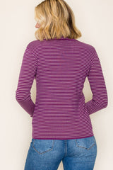 woman wearing a purple and white striped long sleeve top, seen from the back with light blue jeans