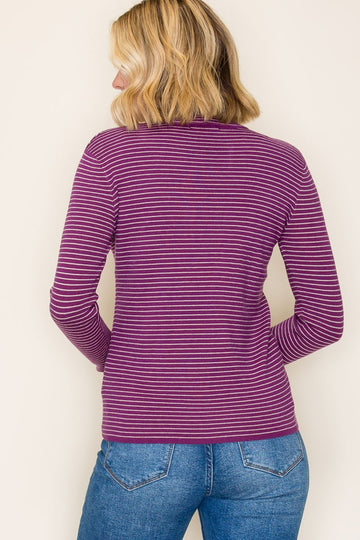 woman wearing a purple and white striped long sleeve top, seen from the back with light blue jeans