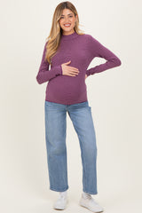 woman wearing a purple striped maternity top and blue jeans, holding her baby bump