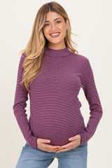 woman wearing a purple and white striped maternity top, smiling and holding her baby bump