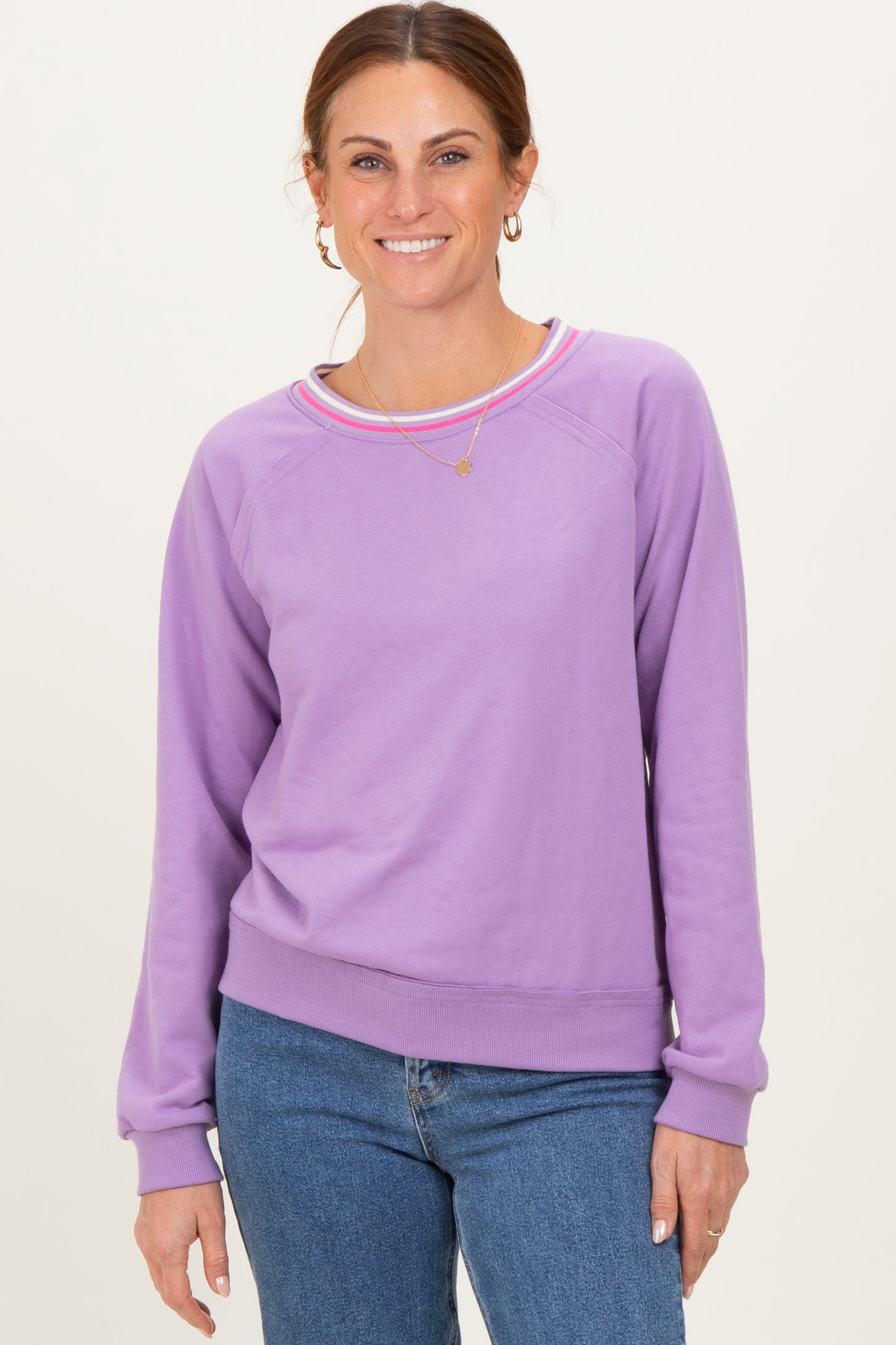 woman wearing a lavender long sleeve sweatshirt with a round neckline and color-blocked trim, smiling at the camera