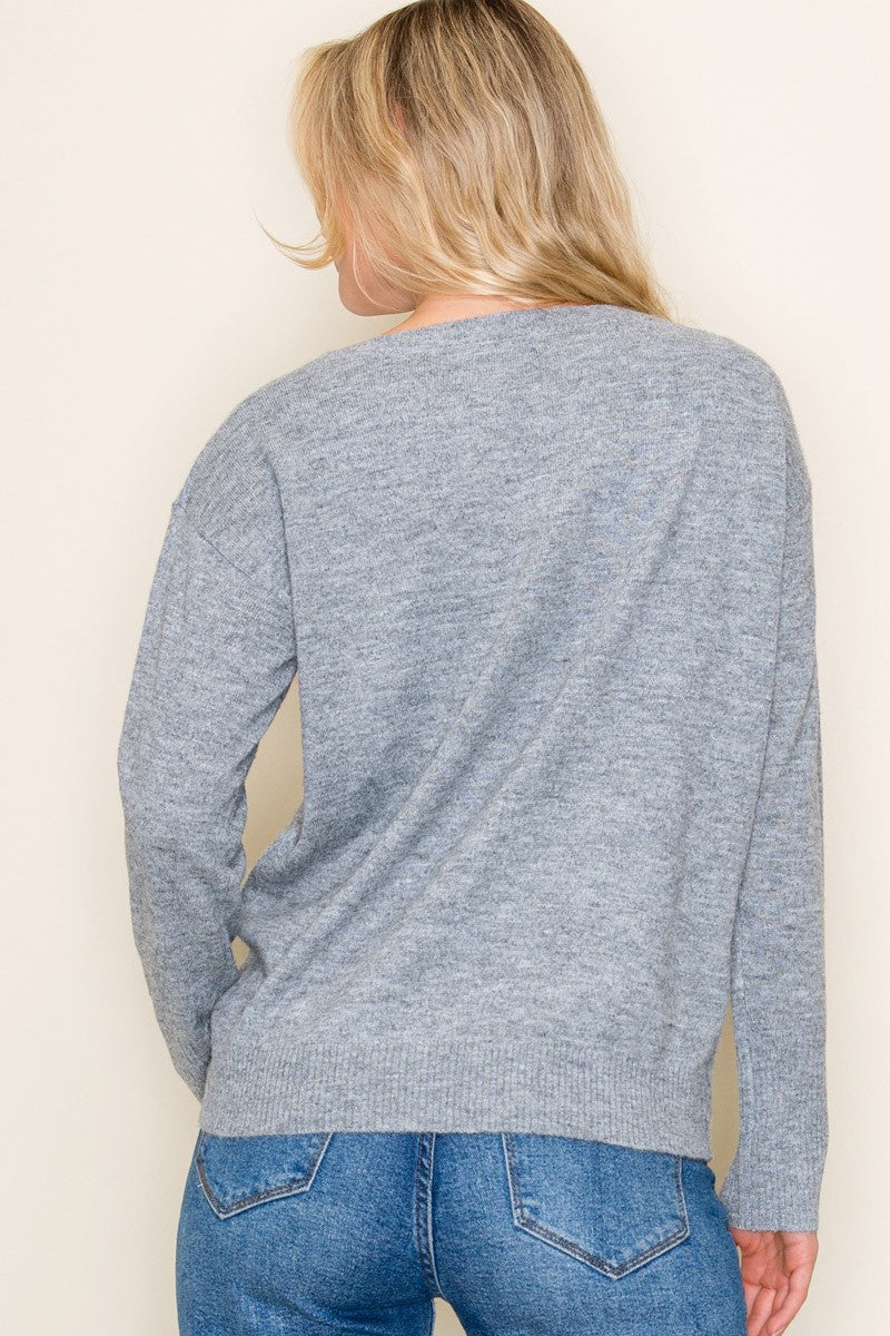 woman wearing a gray long sleeve sweater, shown from the back, with denim jeans