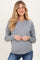 woman wearing a gray long sleeve maternity sweater and showing her baby bump
