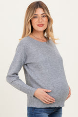 woman wearing a gray maternity sweater and showing her baby bump