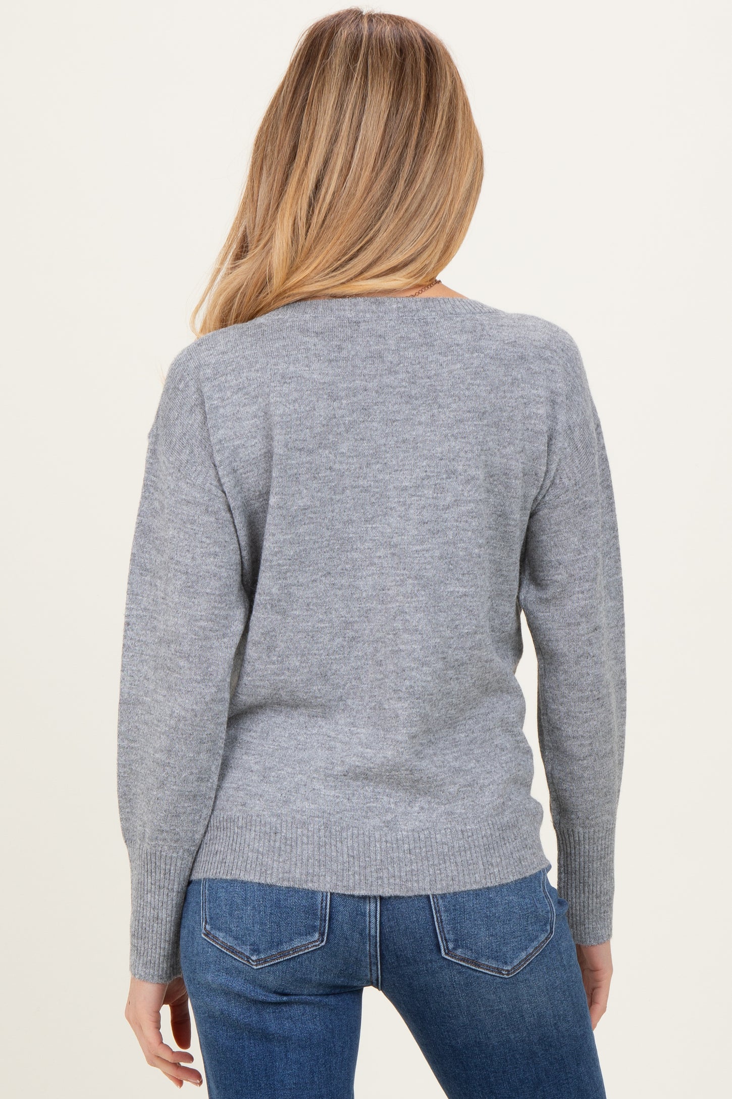 woman wearing a light gray maternity sweater with a relaxed fit and long sleeves, viewed from the back