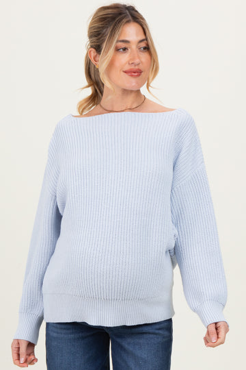 woman wearing a light blue oversized maternity sweater with a ribbed texture and off-the-shoulder neckline, showing her baby bump