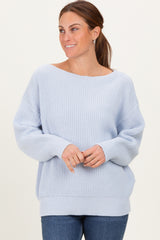 woman wearing a light blue oversized knit sweater with wide neckline and long sleeves, paired with blue jeans