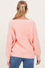 woman wearing a light pink oversized maternity sweater with a ribbed texture and relaxed fit
