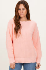 woman wearing a soft pink oversized knit sweater with a wide neckline and ribbed texture, styled with blue jeans