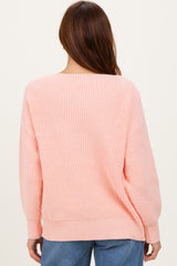 woman wearing a soft pink oversized knit sweater from the back, styled with relaxed-fit denim jeans