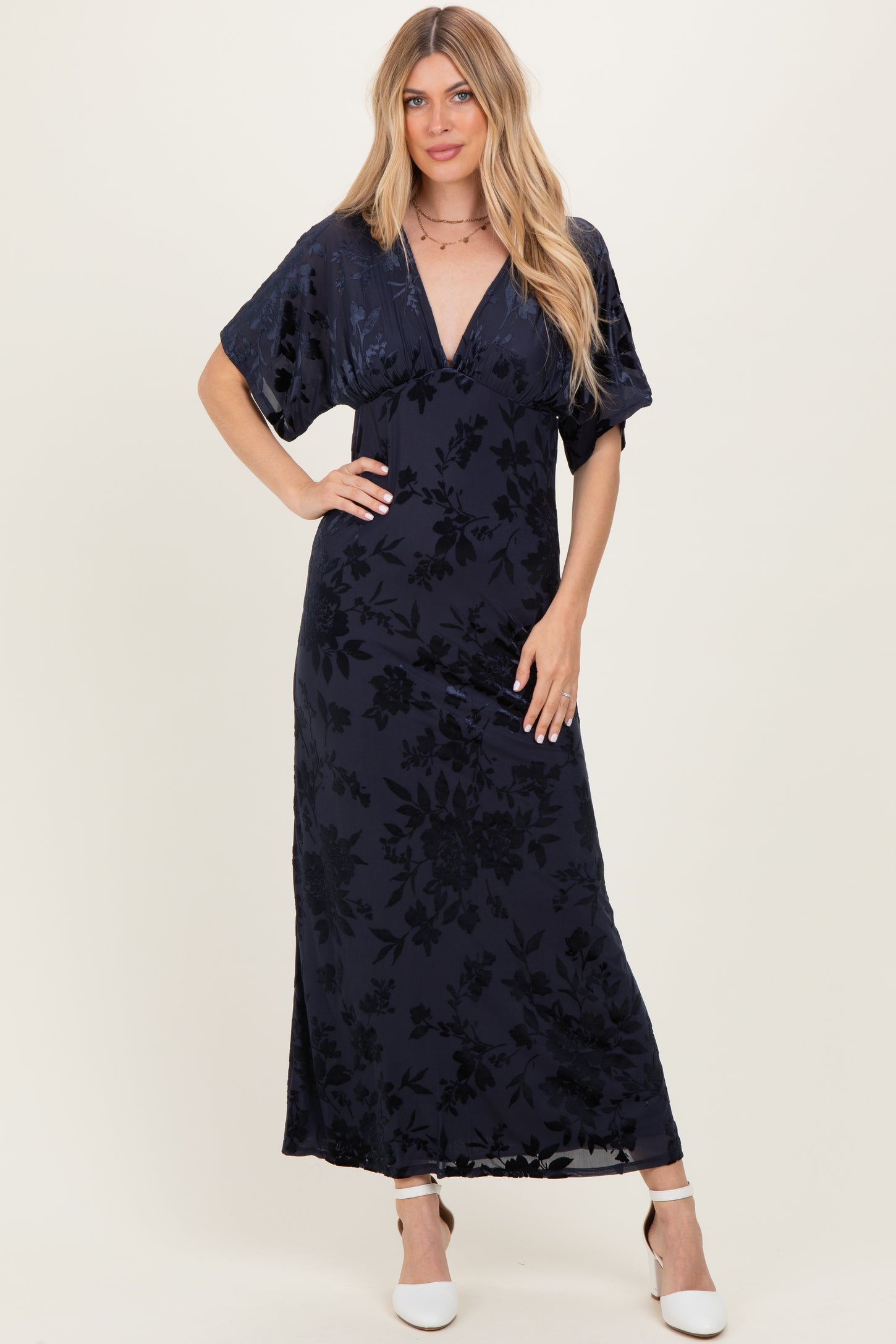 woman wearing a navy blue maxi dress with floral patterns and short flutter sleeves