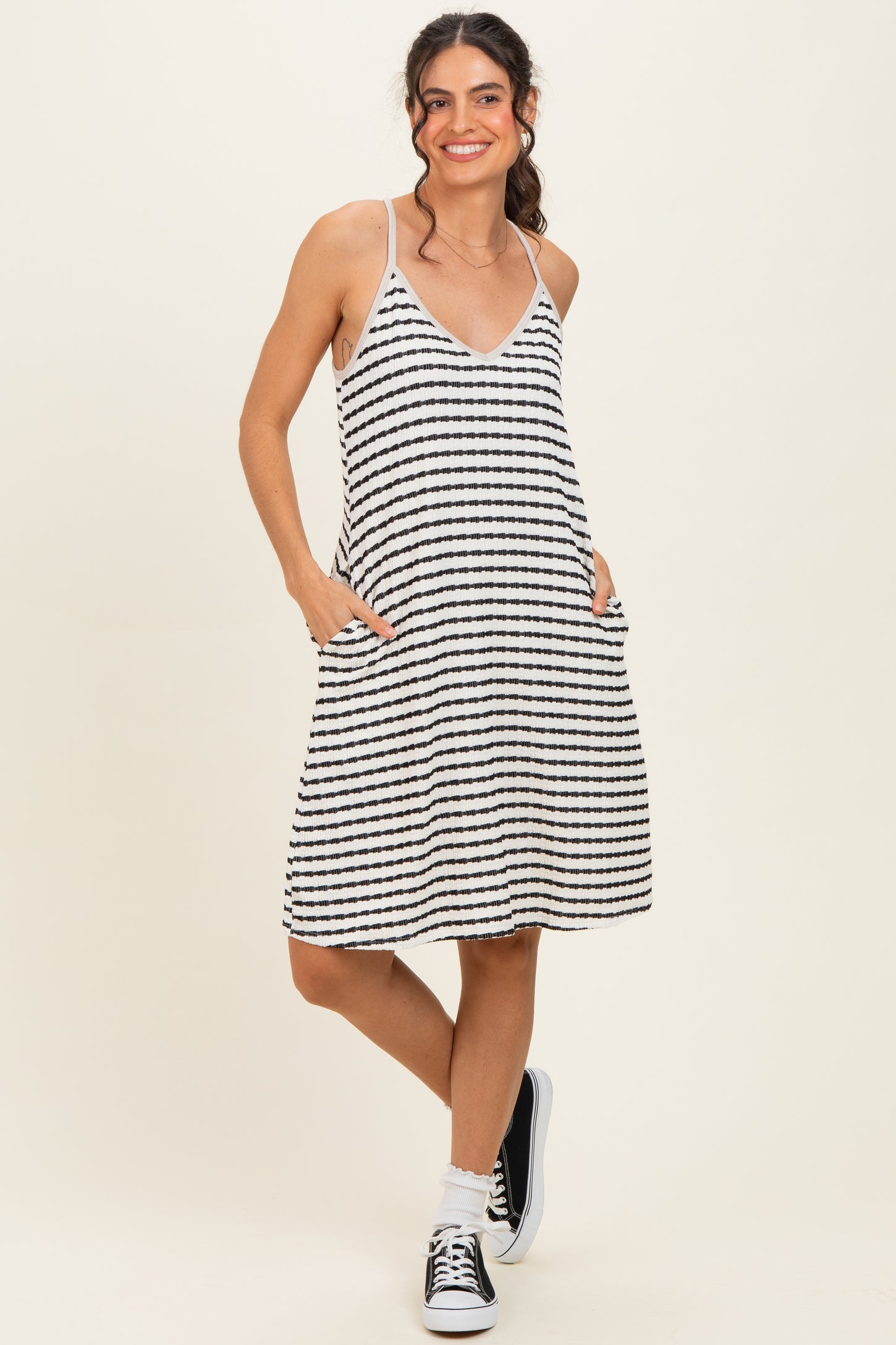 woman wearing a striped black and white sleeveless dress with pockets and a v-neckline