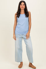woman wearing a light blue ribbed sleeveless top with loose-fitting light wash jeans and brown woven slip-on shoes