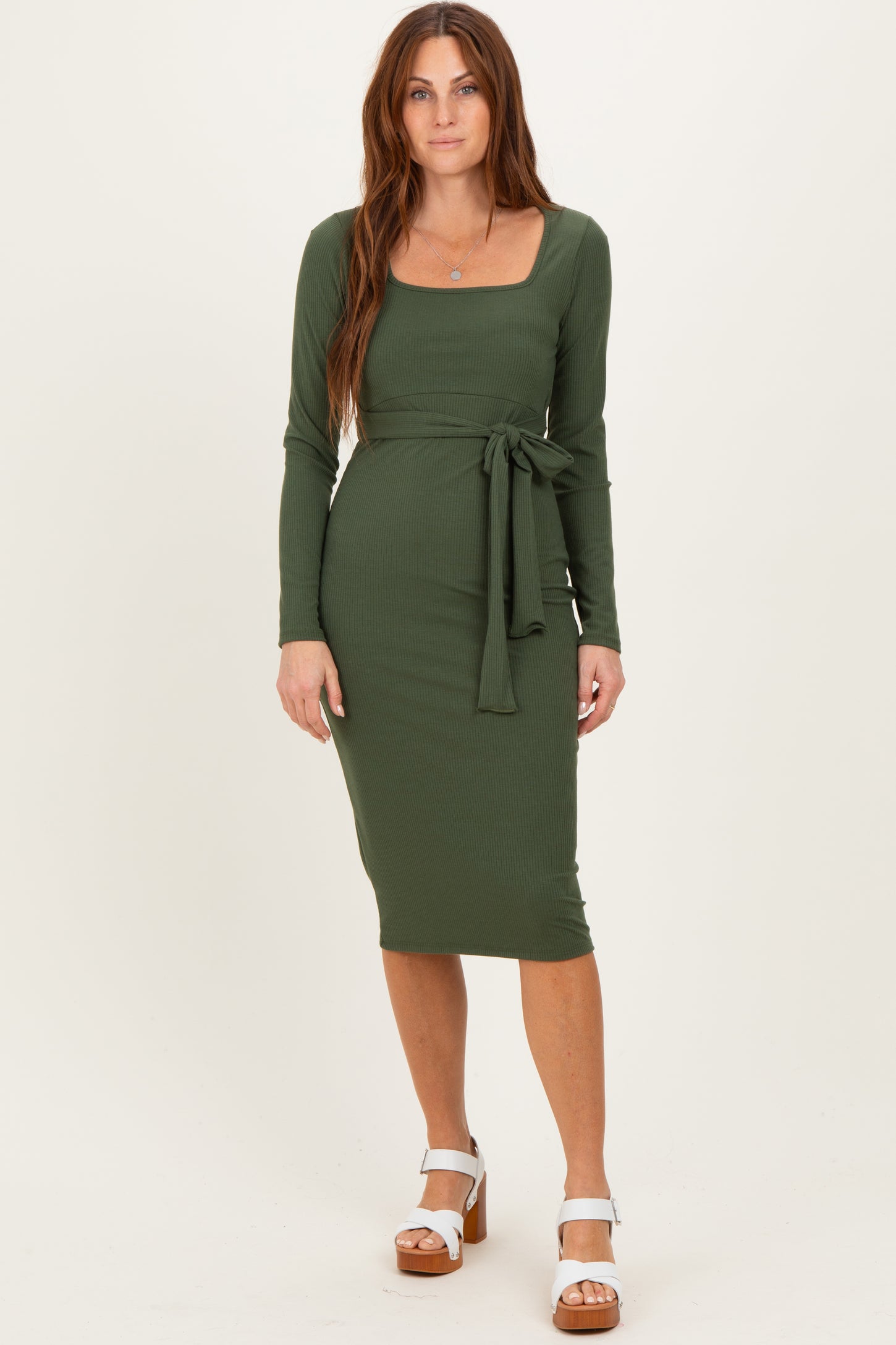 woman wearing a long sleeve olive green ribbed midi dress with a square neckline and a tied waist detail