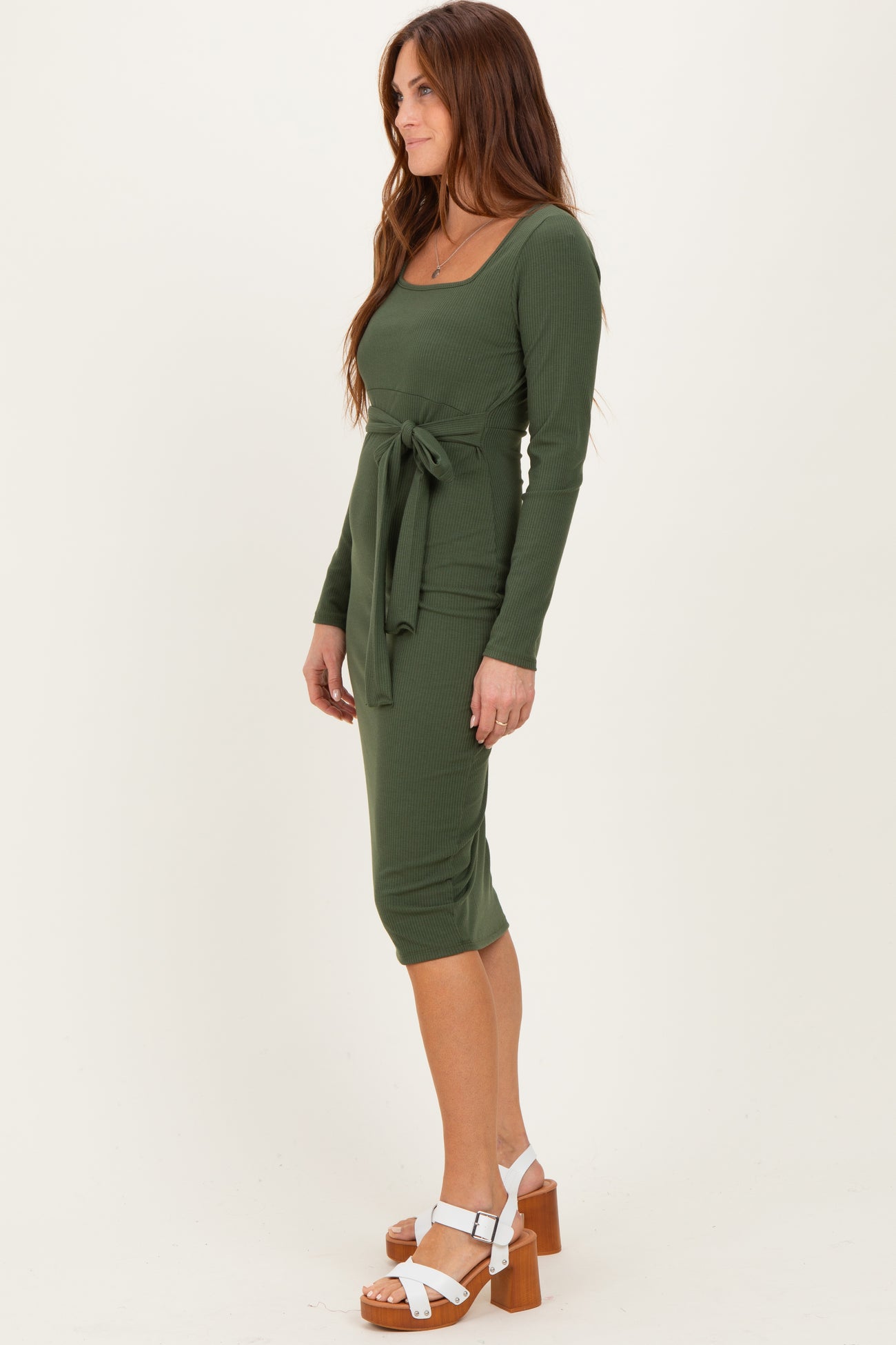 woman wearing a dark green ribbed midi dress with long sleeves and a tie waist detail