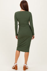 woman wearing a fitted olive green long sleeve midi dress with a ruched detail at the back and high heels