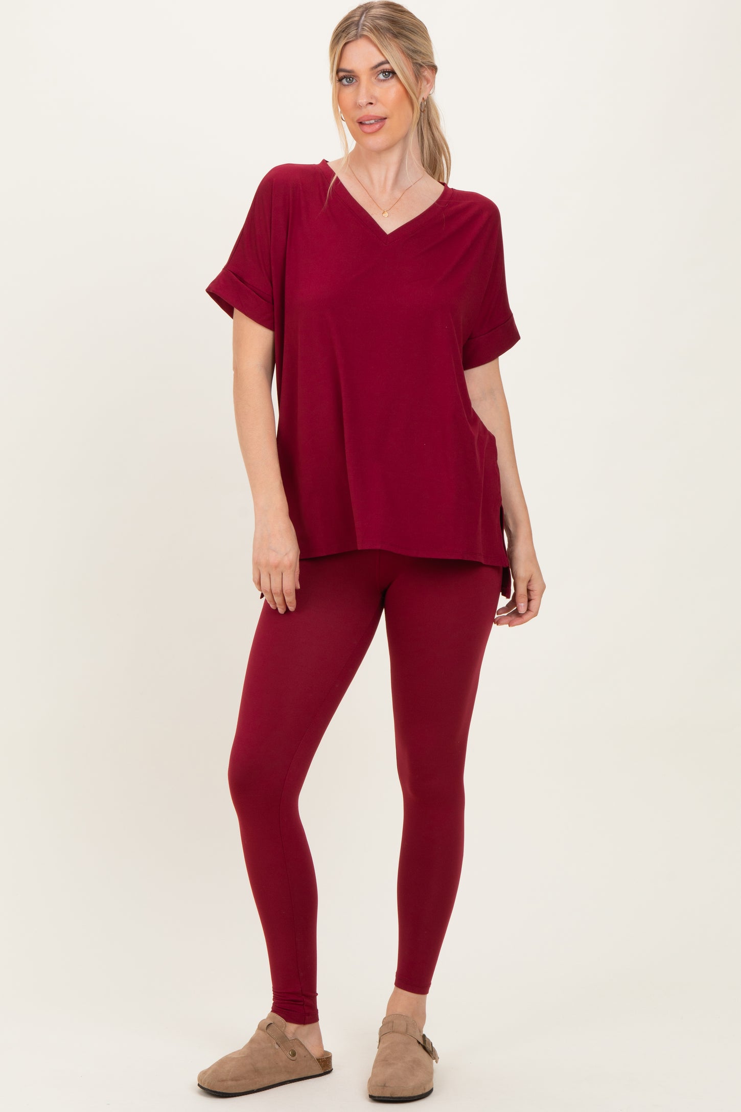 woman wearing a burgundy v-neck oversized top with pocket and matching leggings, styled with tan slip-on shoes