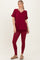 woman wearing a burgundy v-neck oversized top with pocket and matching leggings, styled with tan slip-on shoes