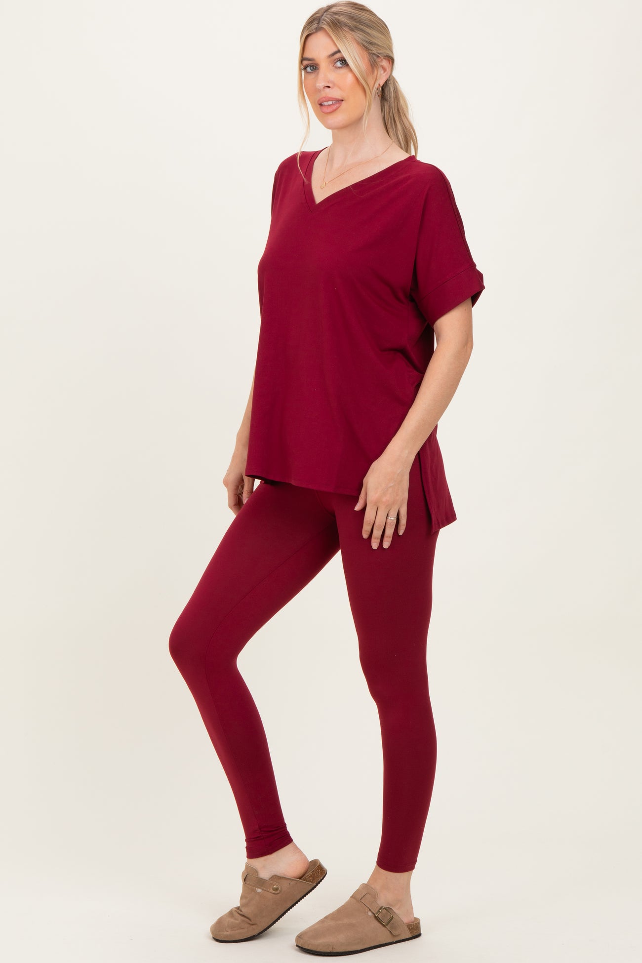 woman wearing a burgundy oversized v-neck top and matching leggings with rolled sleeves and casual shoes