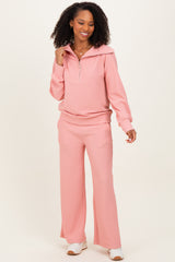 woman wearing a light pink two-piece lounge set with a zip-up hoodie and wide-leg pants