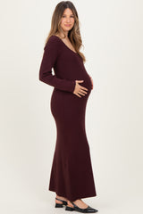 woman wearing a burgundy long sleeve maternity dress showing her baby bump