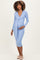 woman wearing a light blue long sleeve maternity dress with a wrap design and holding her baby bump